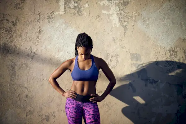 Menstruation, stomach ache and hands of woman in bedroom for indigestion, cramps and illness. Frustrated, gas and stress with girl on bed for constipation, bloating and intestine problems at home