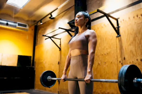 Woman lifting bar bell in gym