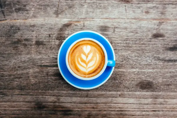 foamy coffee latte with design in blue mug