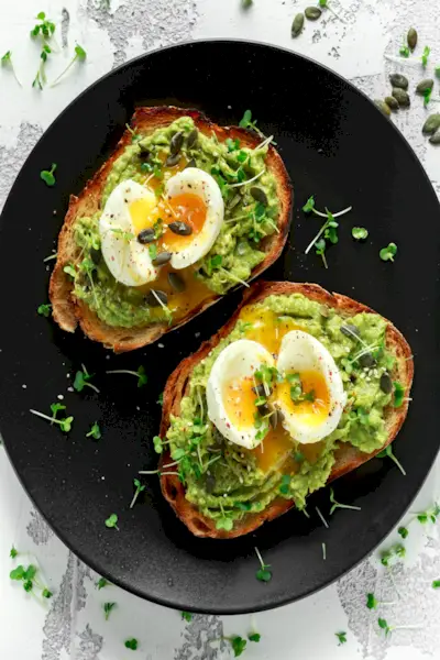 Toast salutari con avocado e uova con semi di zucca e sesamo, cosparsi di insalata di crescione