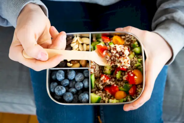 Lunchbox with quinoa salad with tomato and cucumber, blue berry and trail mix