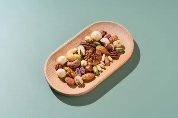 Mixed Nuts in Wooden Dish on Green Background