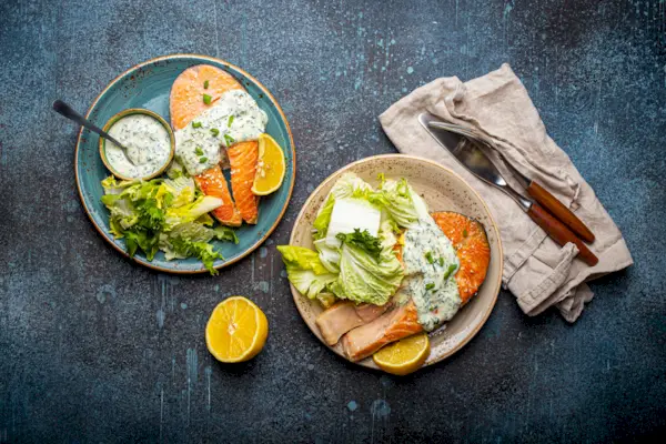 Healthy food meal grilled salmon steaks with dill sauce and salad leafs on two plates