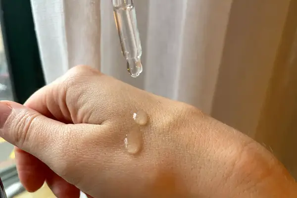 Person applying Rizos Curls Nourish Oil for Hair, Scalp & Body to their hand with a dropper 