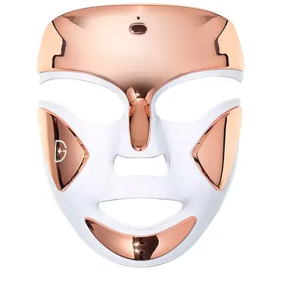 Rose gold and white red light therapy mask that is in the shape of a face