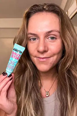 A person holding the Maybelline Baby Skin Instant Pore Eraser Primer tube near their face
