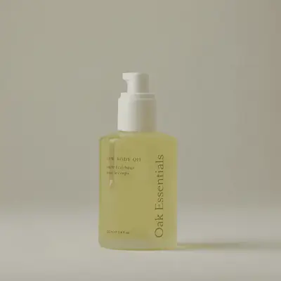 A labeled bottle of Oak Essentials Dew Body Oil on a neutral background