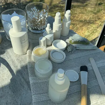 A collection of skincare products on a table including bottles, jars, and a brush