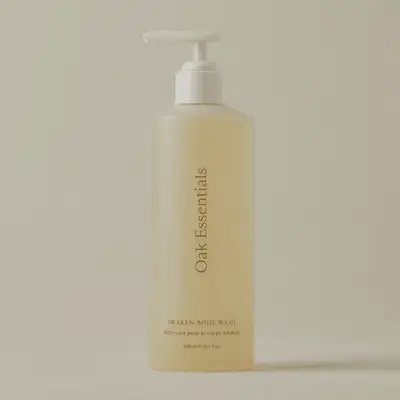 A bottle of Oak Essentials Awaken Body Wash with pump dispenser placed against a neutral background