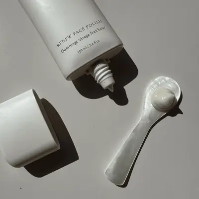 Tube of Renew Face Polish with cap removed and a portion of product on a spoon-like applicator