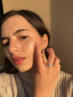 Young woman using face moisturizer