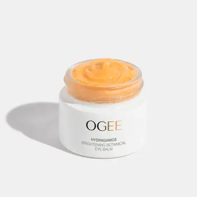Ogee white skincare tub with orange cream coming out the top