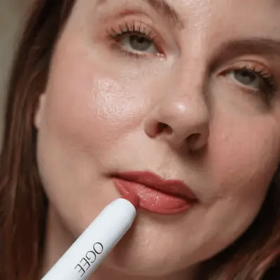 Woman swiping an Ogee Beauty lip oil on her lips