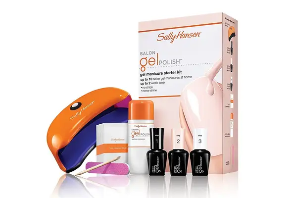 Hand placed into Le Mini Macaron Le Maxi Deluxe Gel Manicure Set nail lamp displayed on marble tabletop