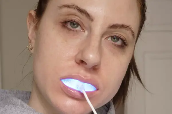 A person using the Glo Science Teeth Whitening Kit light