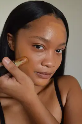 Person applying Bobbi Brown Skin Foundation Stick to their cheek