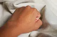 Closed fist with Bobbi Brown Skin Foundation Stick on the back of it 