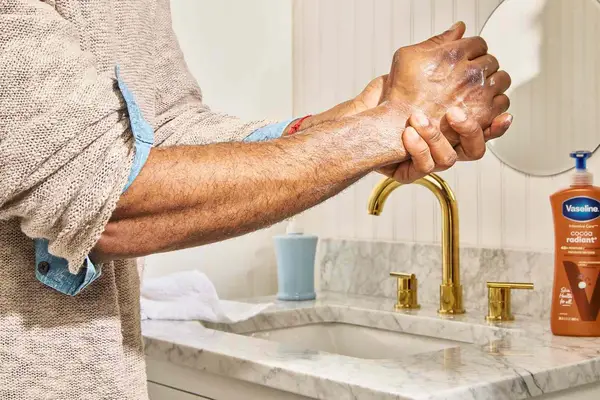 a person applying Vaseline Intensive Care Cocoa Radiant Smoothing Body Butter to their hands