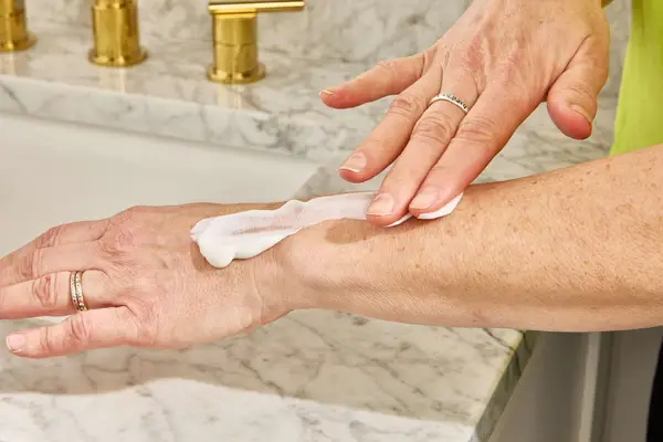 A person applies Acure Seriously Soothing 24hr Moisture Lotion to their forearm