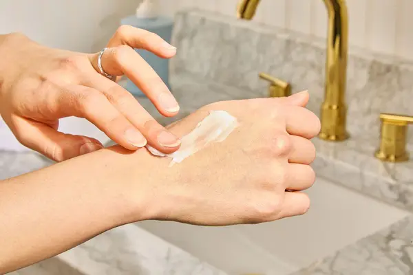 Person applies Aveeno Daily Moisturizing Lotion to the back of their hand