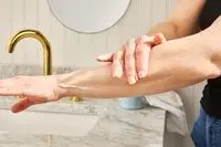 Person rubs CeraVe Daily Moisturizing Lotion into their forearm