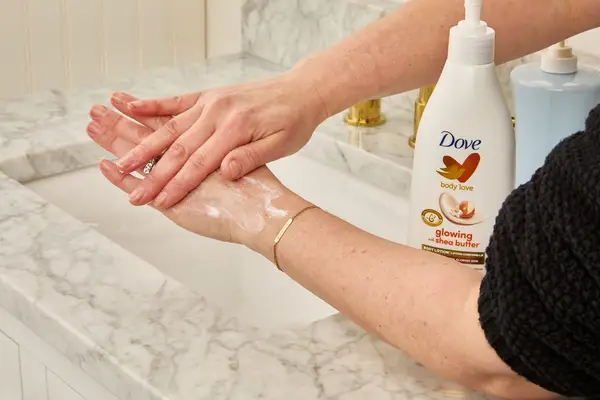 a tester rubs Dove Body Love Glowing Care Body Lotion on their hands
