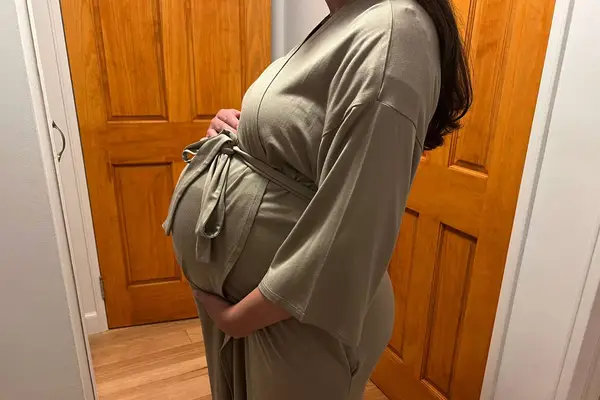 A person wears the Storq Feel Good Delivery Robe in front of wood doors