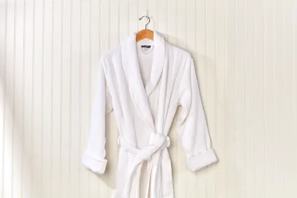 The Brooklinen Super-Plush Robe on a hanger on cream wall