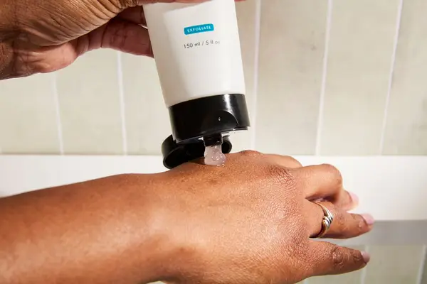 A person dispensing SkinCeuticals Micro-Exfoliating Scrub Smoothing Polish on the back of hand