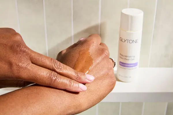A peson rubbing Glytone Rejuvenating Mini Peel Gel onto back of their hand