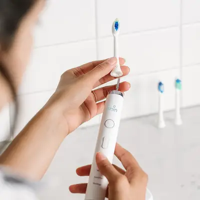Shyn toothbrush being replaced in a white tile bathroom