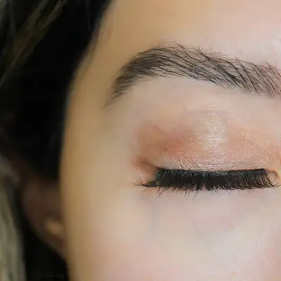 Kiss My Lash But Better false lash strip held in rose gold tweezers