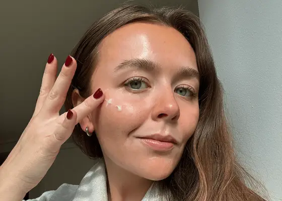 byrdie editor holly rhue applying moisturizer to apples of cheeks