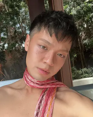 Derek with a pink scarf around his neck and glowy skin