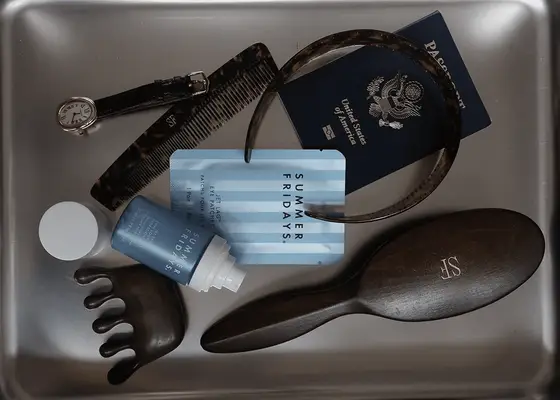 TSA bin with passport, brush, wallet, clips, and beauty products