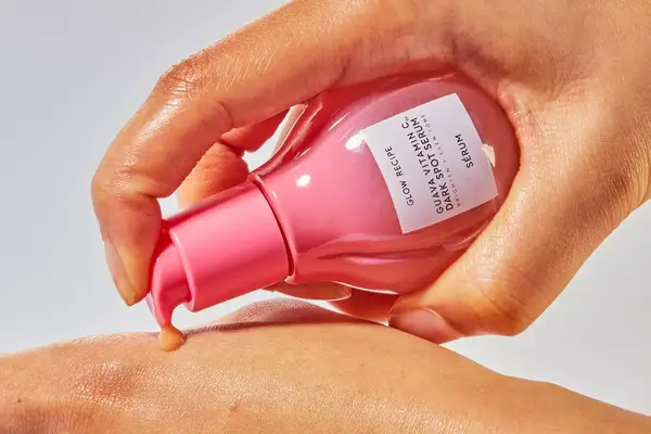 A hand squeezing out a small sample of Glow Recipe Guava Vitamin C Dark Spot Serum on the back of a hand 