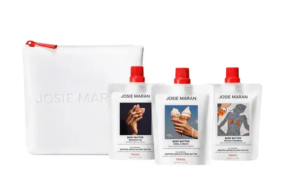 Three white Josie Maran body butter pouches with red caps and a mini product bag