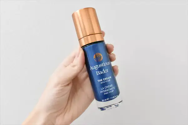 Hand holding a bottle of Augustinus Bader The Rich Cream