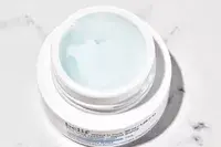 Open jar of belif The True Cream Aqua Bomb displayed on a marbled counter