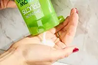 A person pouring Garnier Fructis Grow Strong Shampoo into their hands