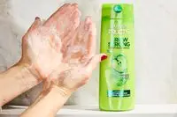 A person lathering the Garnier Fructis Grow Strong Shampoo onto their hands