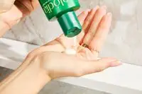 A person pouring Alodia Nourish & Hydrate Creme Shampoo into their hand