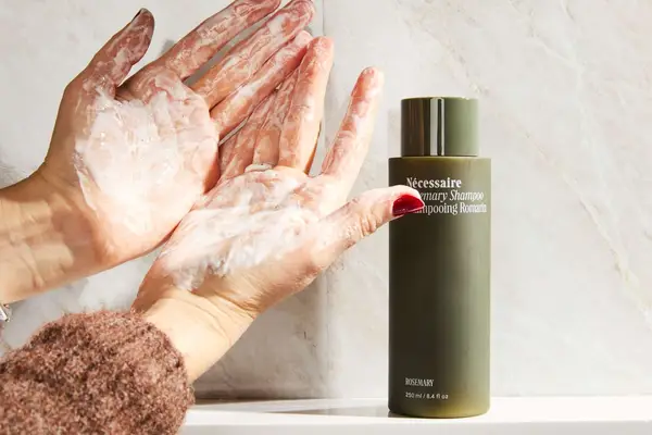 A person lathering the Nécessaire Rosemary Shampoo in their hands