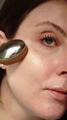 model applies foundation to the skin with a foundation brush