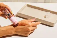 Close-up of a peron applying Maybelline New York Instant Age Rewind Perfector 4-In-1 Glow Makeup to the side of their hand