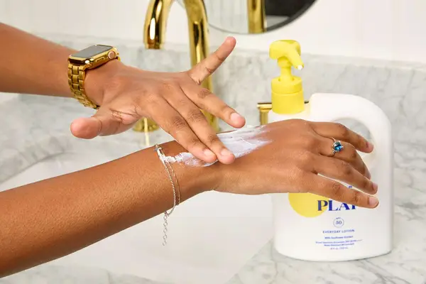 A person applying Supergoop! Play Everyday Lotion to their arm
